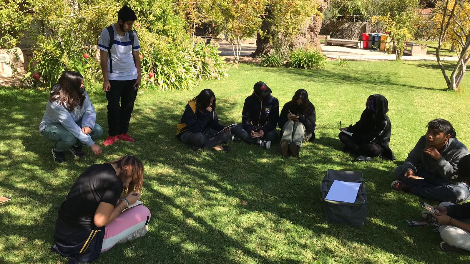 Estudiantes sentados en los pastos del Jardín Poético del museo, desarrollando actividades de la Cosecha Literaria