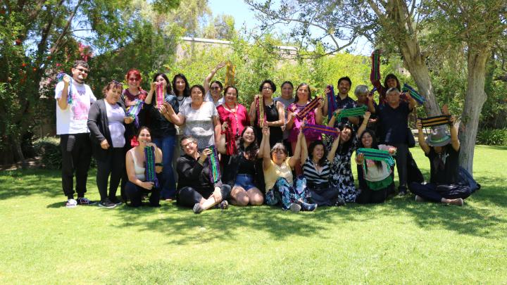 Grupo de beneficiarias y beneficiarios del taller posan junto a sus relatoras con sus tejidos