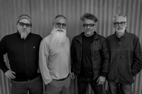 Cuatro hombres de pie mirando de frente. Son los músicos de esta cita.